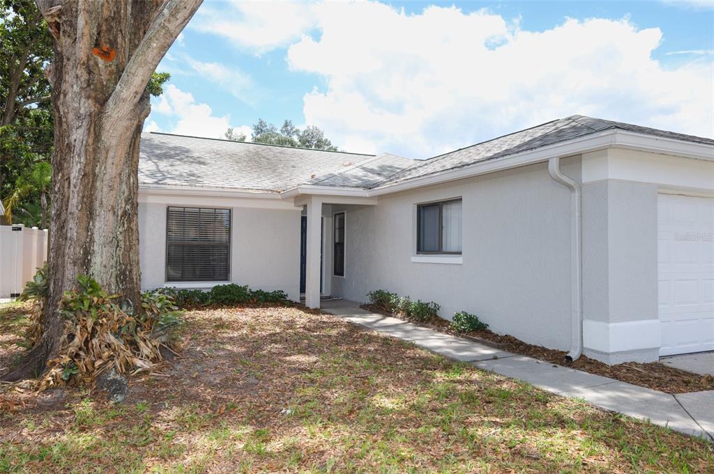A single-story house with a light gray exterior, a concrete walkway, and a large tree — 1047 ABELL CIRCLE, OVIEDO, FL