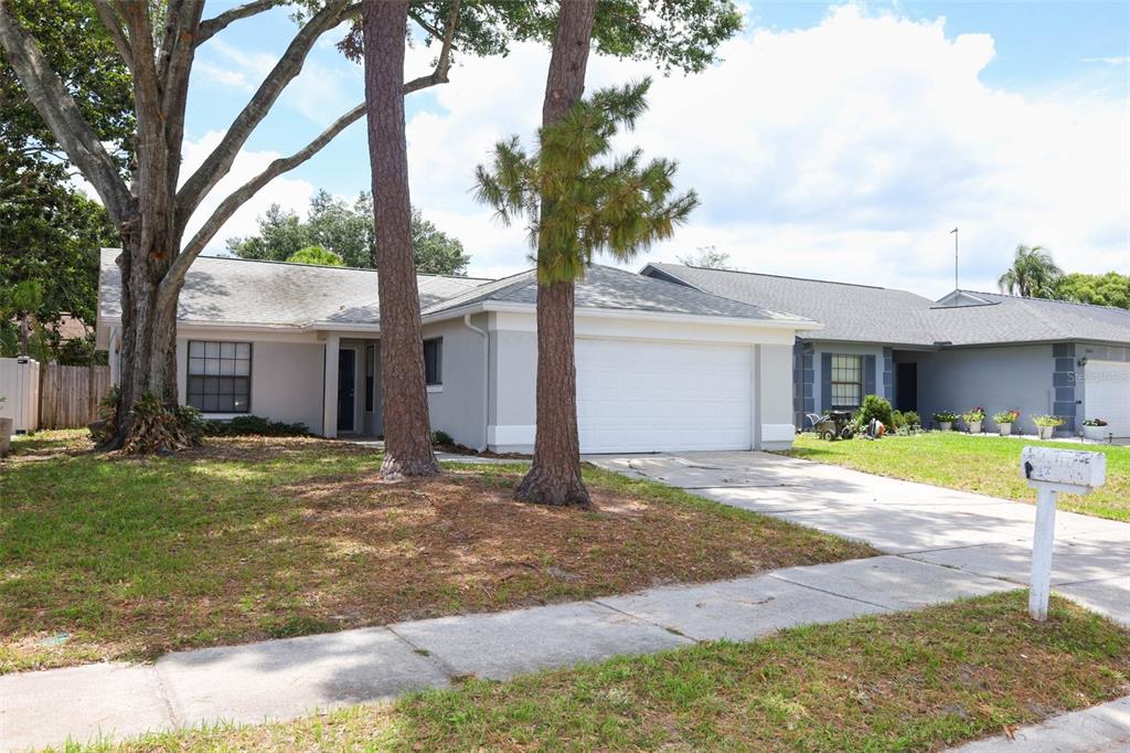 A single-story house with a white garage, gray exterior, and two large pine trees — 1047 ABELL CIRCLE, OVIEDO, FL