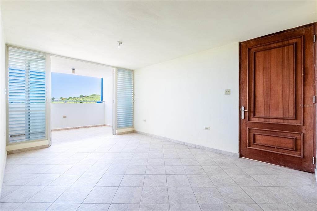 An empty room with tiled floors, a wooden door, and an open balcony with railings — 000 CAMINO LOS VÉLEZ, CABO ROJO, PR