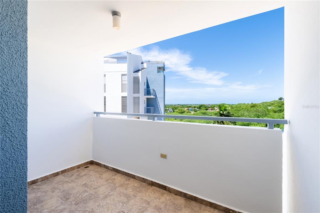A balcony with tiled flooring, a white wall, and a metal railing overlooking a landscape — 000 CAMINO LOS VÉLEZ, CABO ROJO, PR