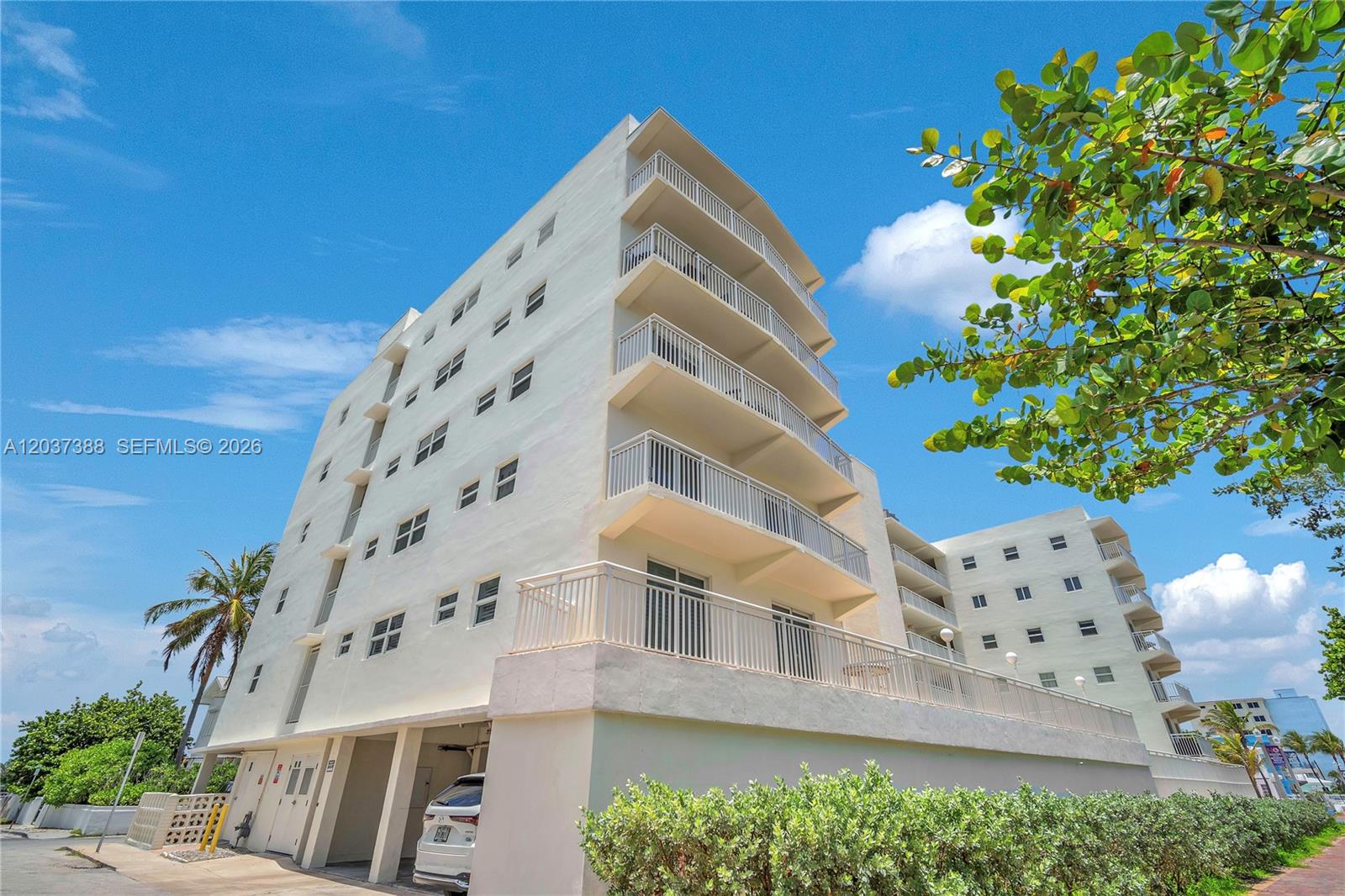 A low-angle view of a multi-story white apartment building with stacked balconies and parking — 901 S Surf Rd # 506, Hollywood FL 33019, HOLLYWOOD, FL