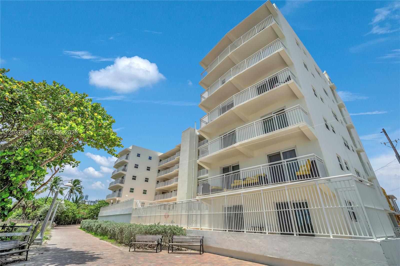 A multi-story white apartment building stands next to a paved walkway and green trees — 901 S Surf Rd # 506, Hollywood FL 33019, HOLLYWOOD, FL