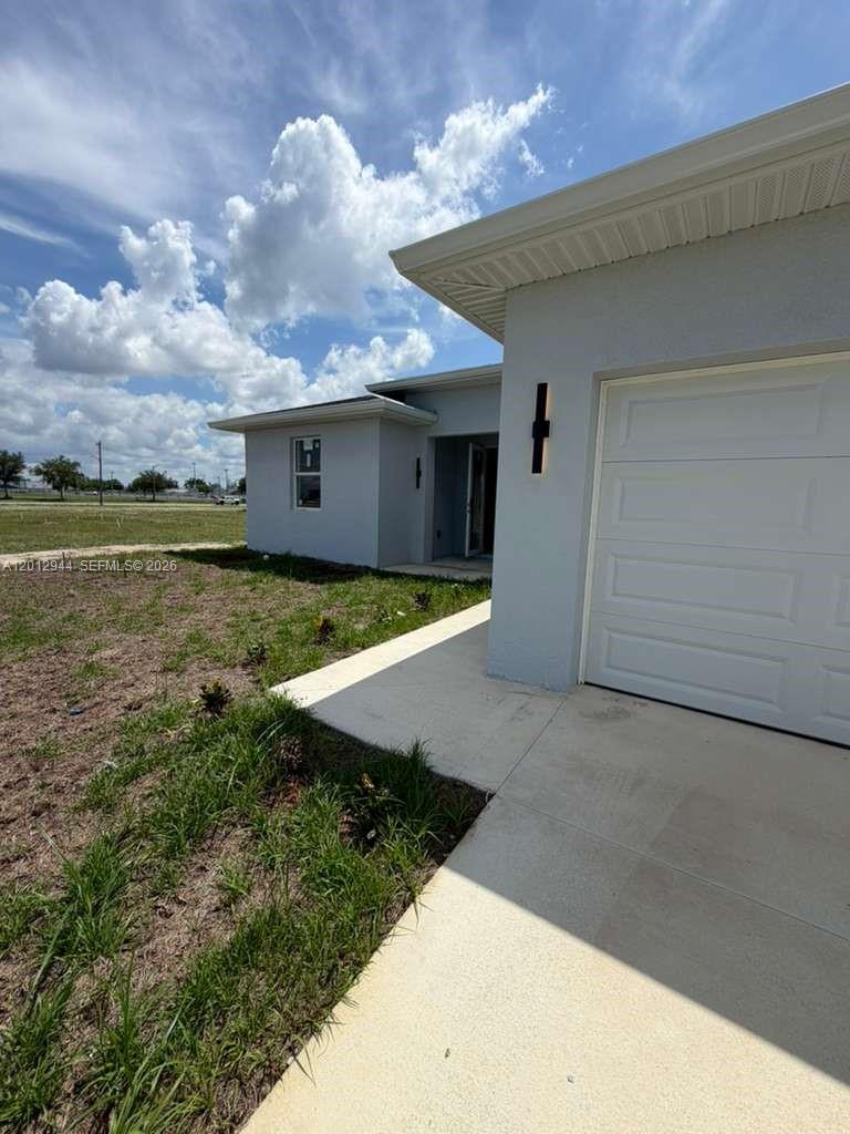 A light gray house exterior features a white garage door and a concrete driveway — 3629 E Gator Cir, Cape Coral FL 33909, CAPE CORAL, FL