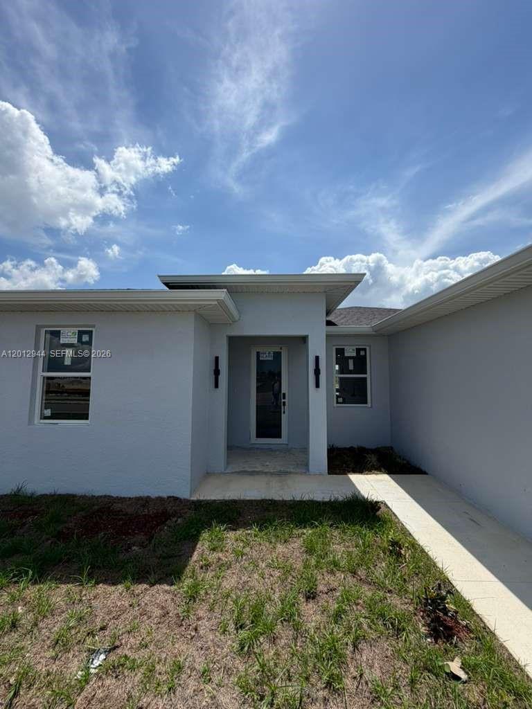 The exterior of a light gray, single-story house features a recessed front entrance — 3629 E Gator Cir, Cape Coral FL 33909, CAPE CORAL, FL