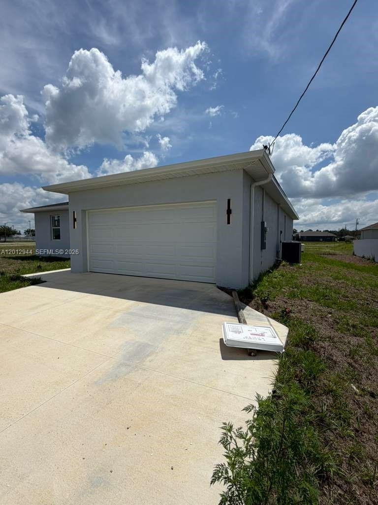 A gray single-story house exterior features a white garage door and a concrete driveway — 3629 E Gator Cir, Cape Coral FL 33909, CAPE CORAL, FL