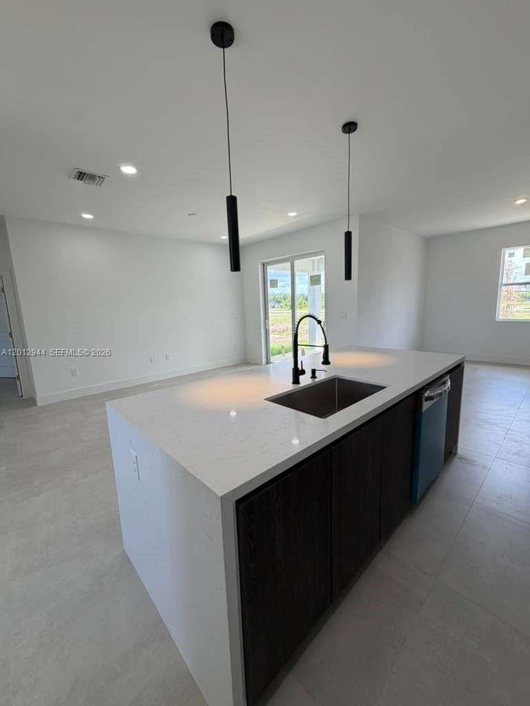 A modern kitchen island with a white countertop and dark cabinets sits in an open room — 3629 E Gator Cir, Cape Coral FL 33909, CAPE CORAL, FL