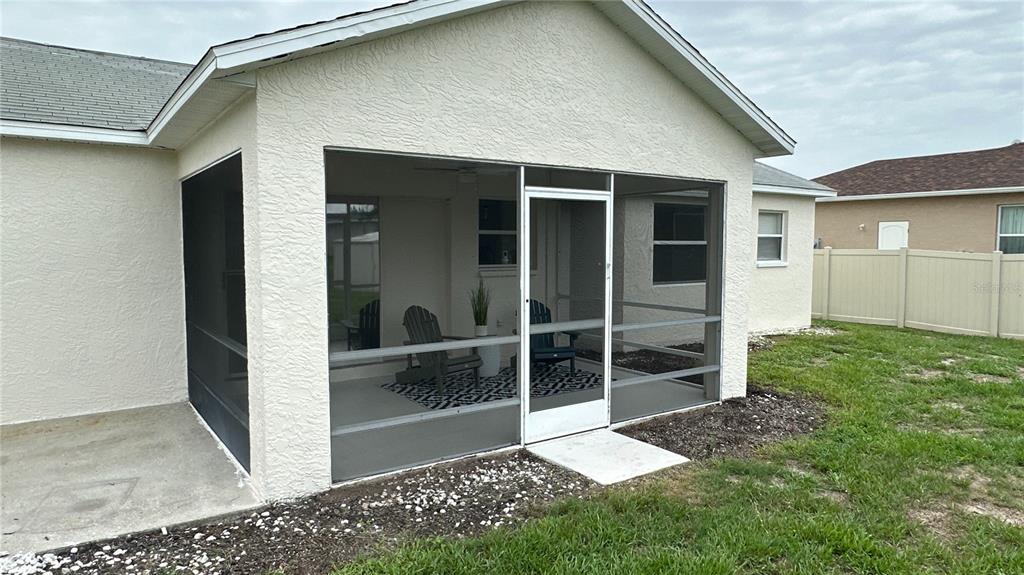 A screened-in patio with a concrete floor and outdoor furniture attached to a house — 11074 CARNEGIE AVENUE, ENGLEWOOD, FL