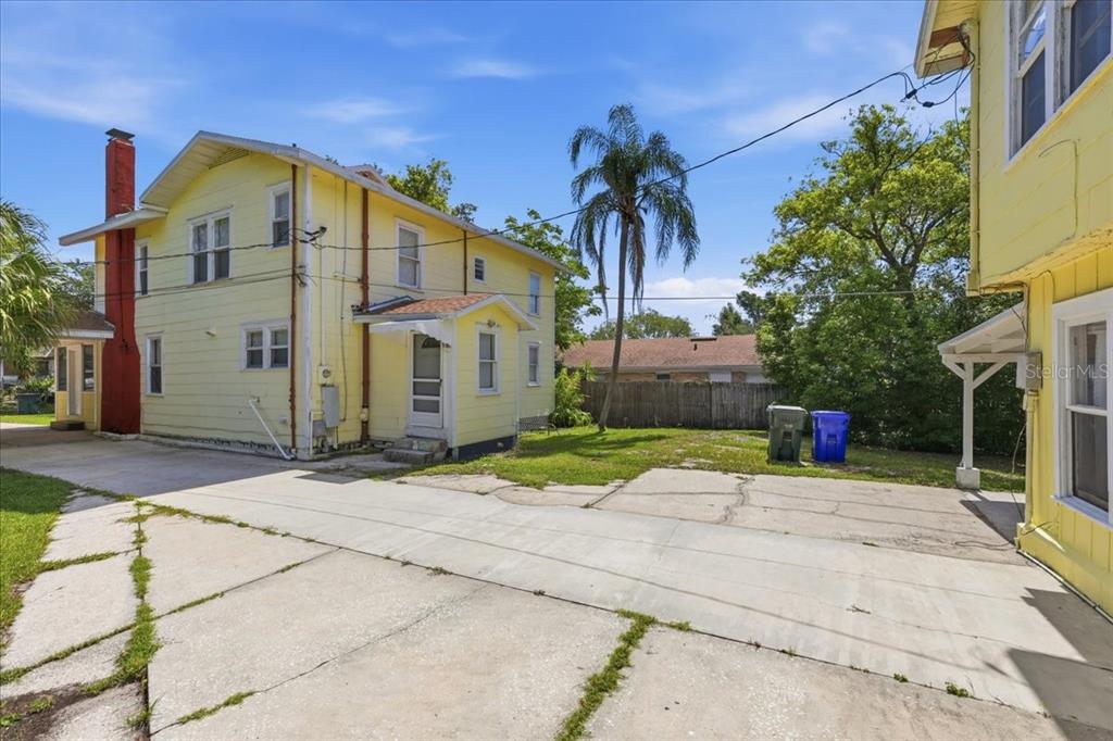 A yellow two-story house with a red chimney stands next to a concrete driveway — 1049 MONROE STREET, LAKELAND, FL