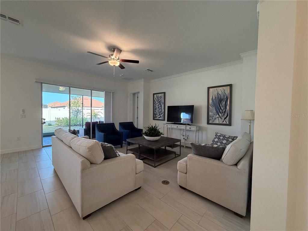 A living room features light tile floors, two beige sofas, two blue armchairs, and a television — 17165 SCUBA CREST STREET, WIMAUMA, FL