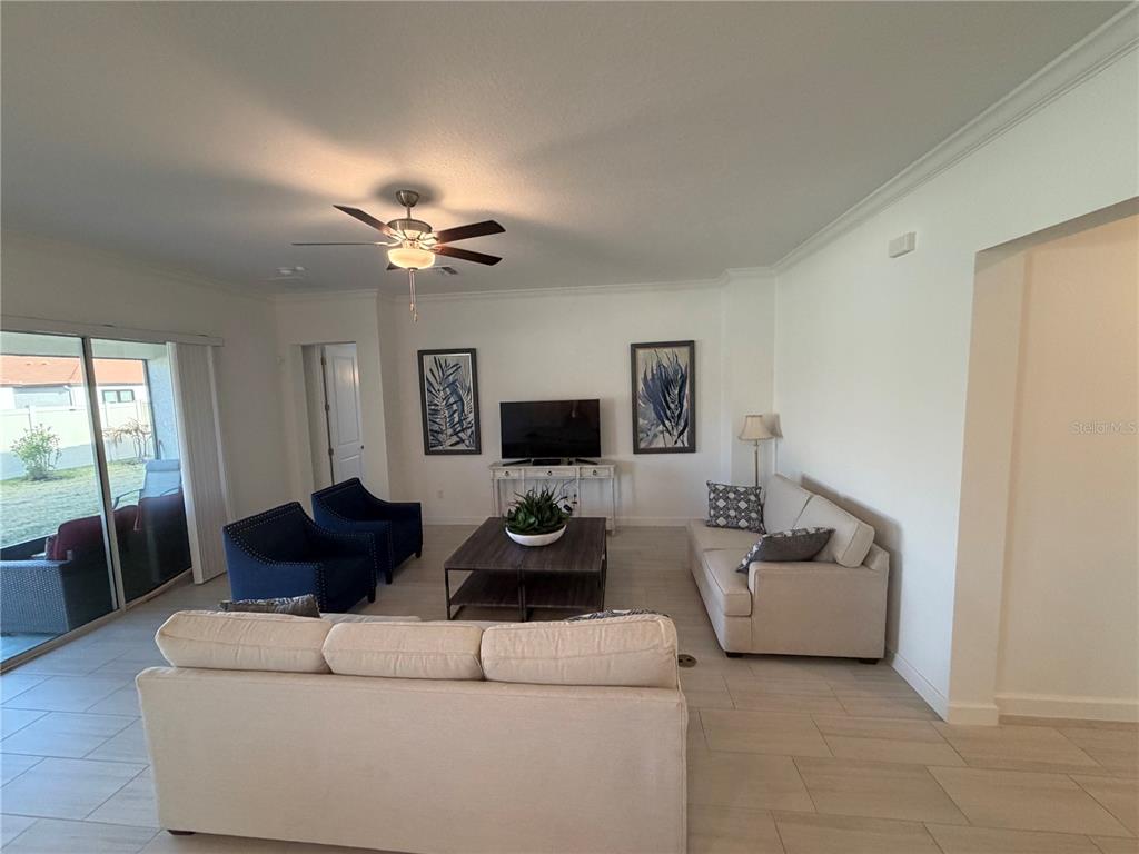 A living room features two beige sofas, two blue armchairs, a coffee table, and a television — 17165 SCUBA CREST STREET, WIMAUMA, FL