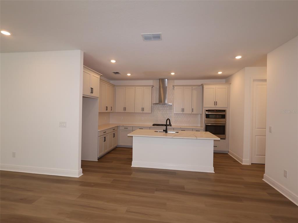 A modern kitchen features light-colored cabinetry, a central island with a sink, and stainless appliances — 4454 SUNSET GARDEN STREET, BRADENTON, FL