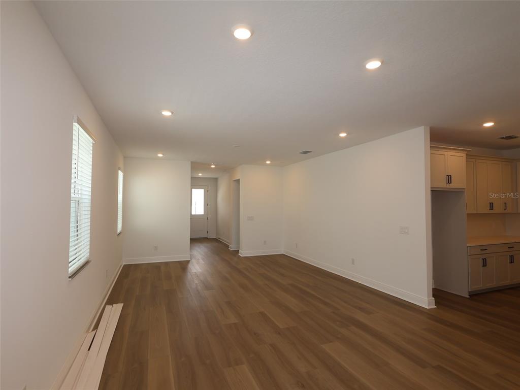 An open-concept living area features light wood-look flooring, recessed lighting, and a kitchen corner — 4454 SUNSET GARDEN STREET, BRADENTON, FL