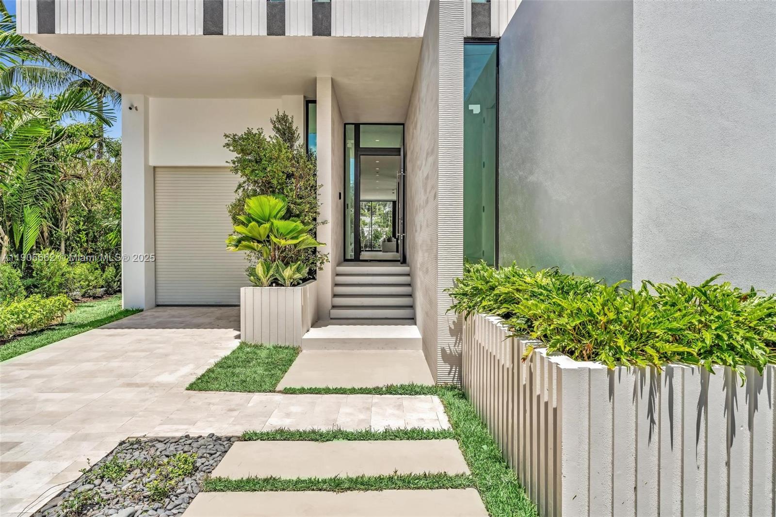 The exterior of a modern home features a glass front door, concrete steps, and planters — 4504 Sheridan Ave, Miami Beach FL 33140, MIAMI BEACH, FL