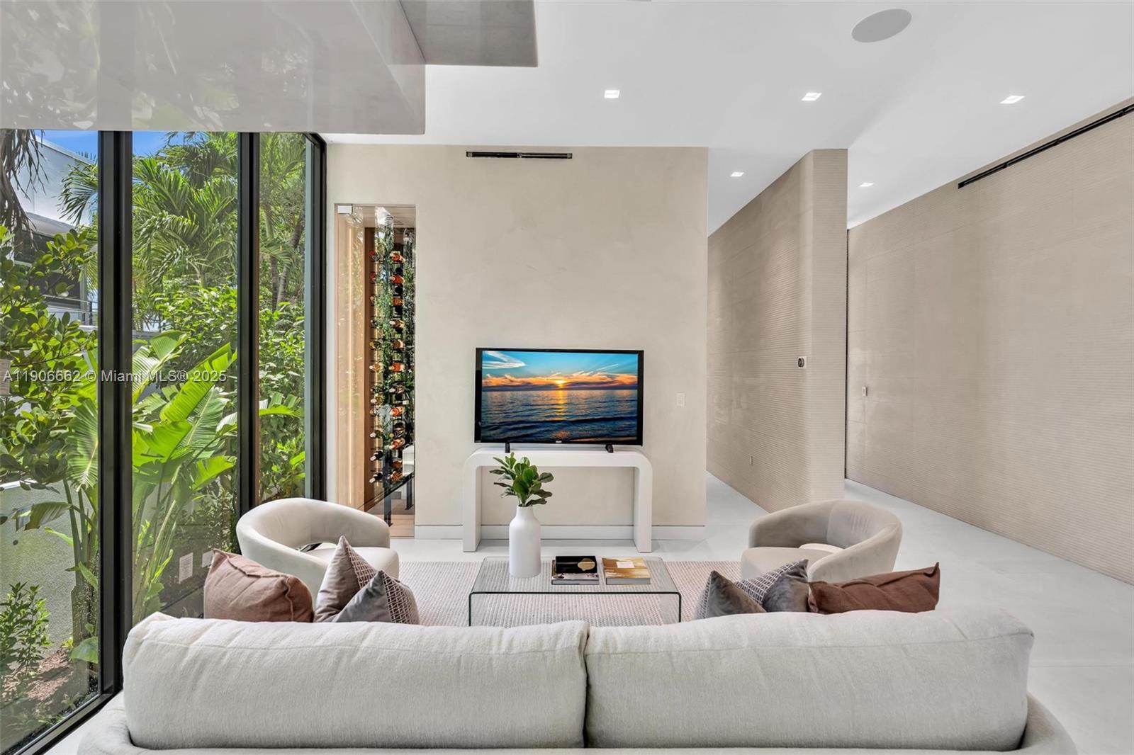 A modern living room features a television, a glass wine display, and floor-to-ceiling windows — 4504 Sheridan Ave, Miami Beach FL 33140, MIAMI BEACH, FL