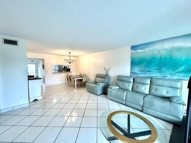 A living room with light-colored tile floors, a blue sofa, and a large ocean mural — 3601 Inverrary Drive # 306, Lauderhill FL 33319, LAUDERHILL, FL