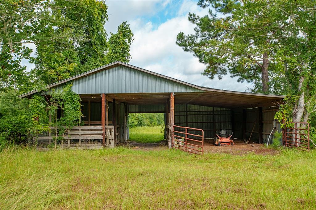 A metal-roofed pole barn with a dirt floor stands in a grassy field — 25518 NW COUNTY ROAD 241, ALACHUA, FL
