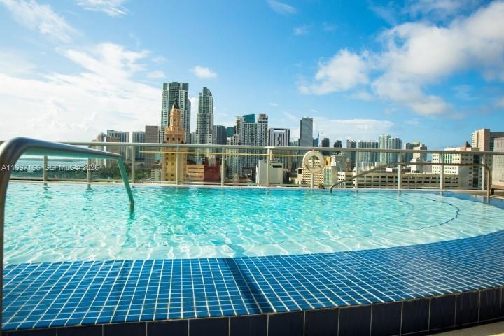 An infinity pool overlooks the Miami skyline under a blue sky with clouds — 888 Biscayne Blvd # 2211, Miami FL 33132, MIAMI, FL