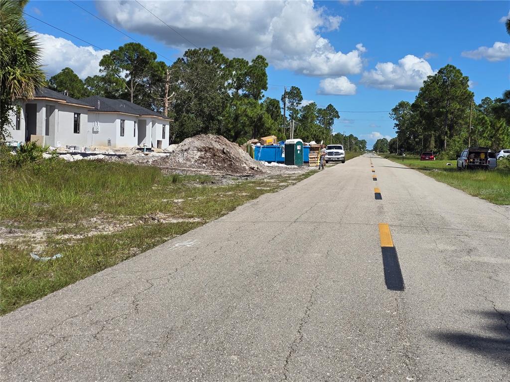A new house under construction sits beside a road with a dumpster and portable toilet — 1111 NIMITZ BOULEVARD, LEHIGH ACRES, FL