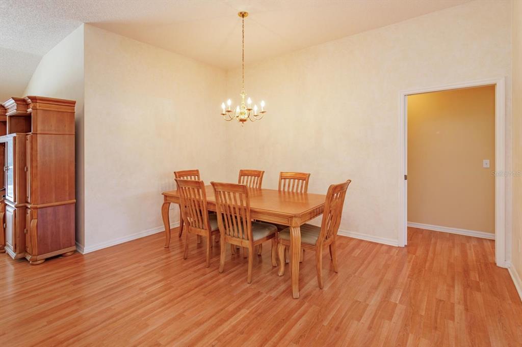 A dining room with a wooden table, six chairs, a chandelier, and light-colored walls — 1115 SALDIVAR ROAD, LADY LAKE, FL