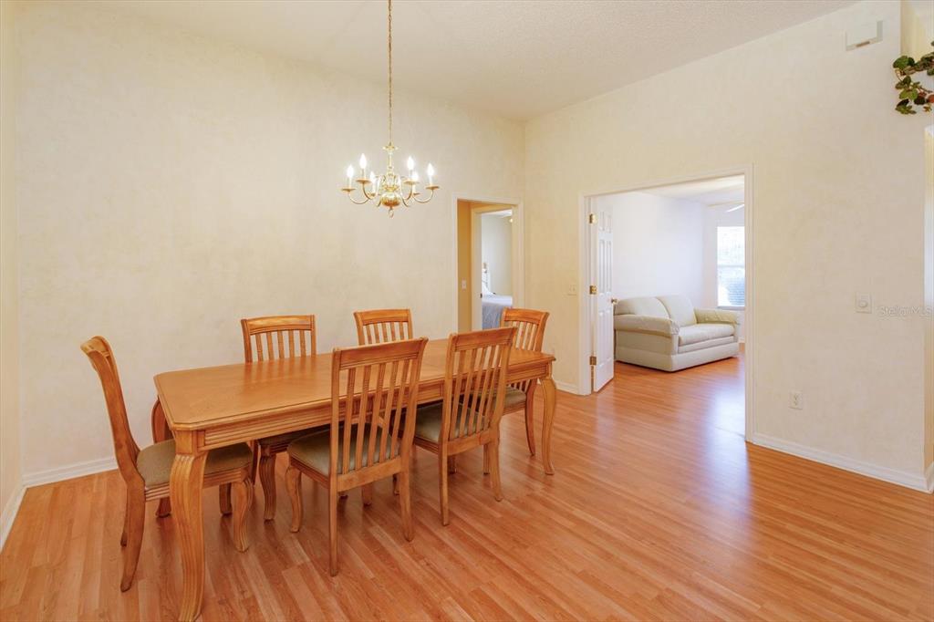 A dining room features a wooden table, six chairs, a chandelier, and light-colored walls — 1115 SALDIVAR ROAD, LADY LAKE, FL