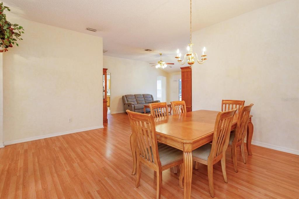 A dining room with a wooden table and chairs sits adjacent to a living area — 1115 SALDIVAR ROAD, LADY LAKE, FL