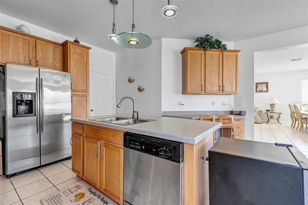 A kitchen features wood cabinets, stainless steel appliances, a center island, and tile flooring — 2013 CROSSVINE LANE, CASSELBERRY, FL