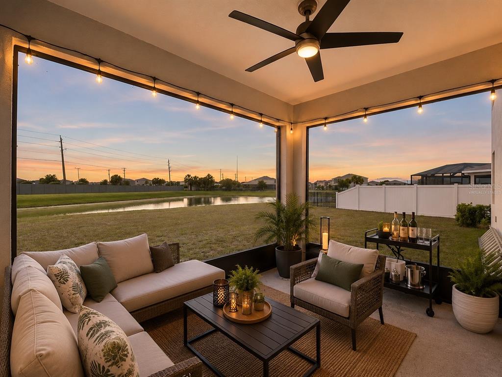 A covered patio features outdoor furniture, a ceiling fan, string lights, and a pond view — 4020 LIVELY CORAL PLACE, BRADENTON, FL