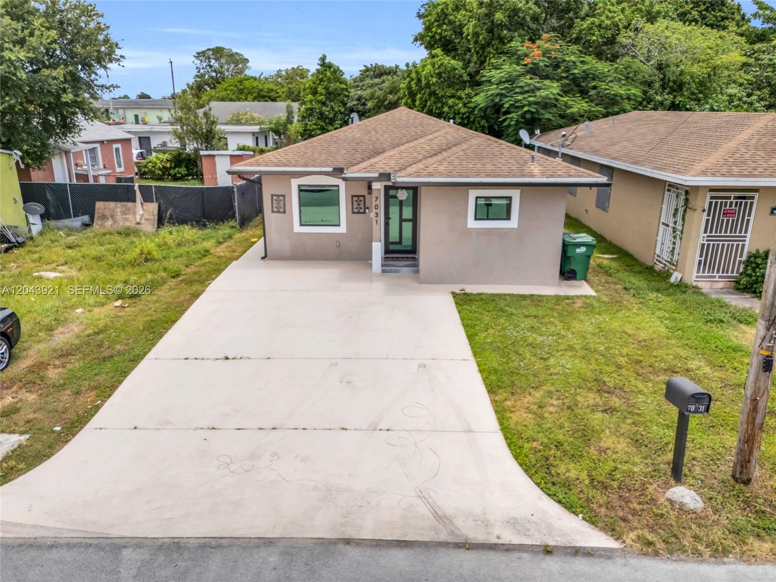 A single-story house with a tan stucco exterior, a brown shingled roof, and a concrete driveway — 7031 NW 20th Ave, Miami FL 33147, MIAMI, FL