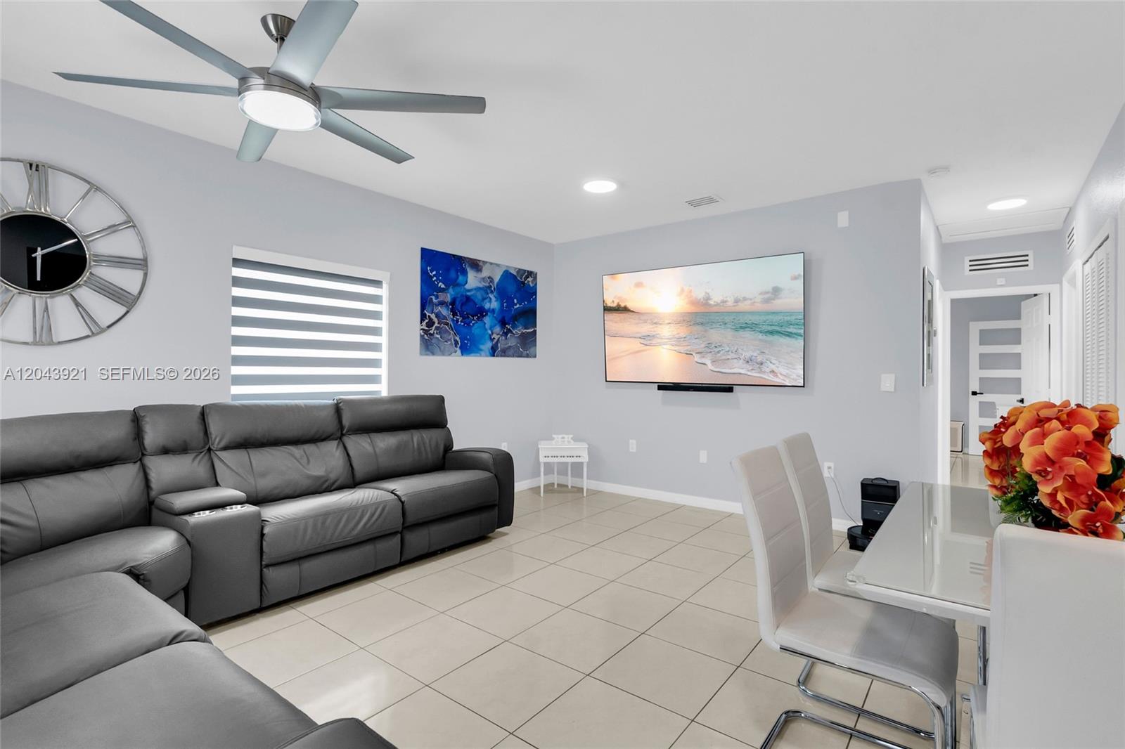 A living room features a grey sectional sofa, a wall-mounted television, and a dining area — 7031 NW 20th Ave, Miami FL 33147, MIAMI, FL