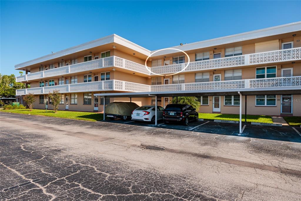A three-story apartment building exterior features a circled second-floor balcony and covered parking spaces — 4915 BAY STREET NE UNIT 331, ST PETERSBURG, FL