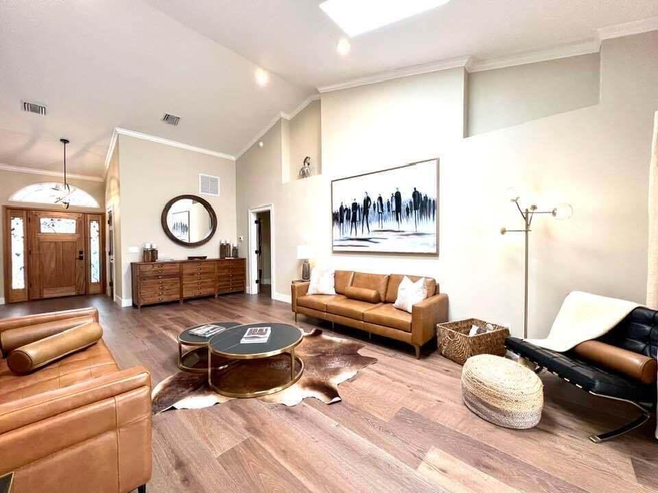 A living room features vaulted ceilings, wood flooring, leather sofas, and a large abstract painting — 14256 Greentree Trail, Wellington FL 33414, WELLINGTON, FL