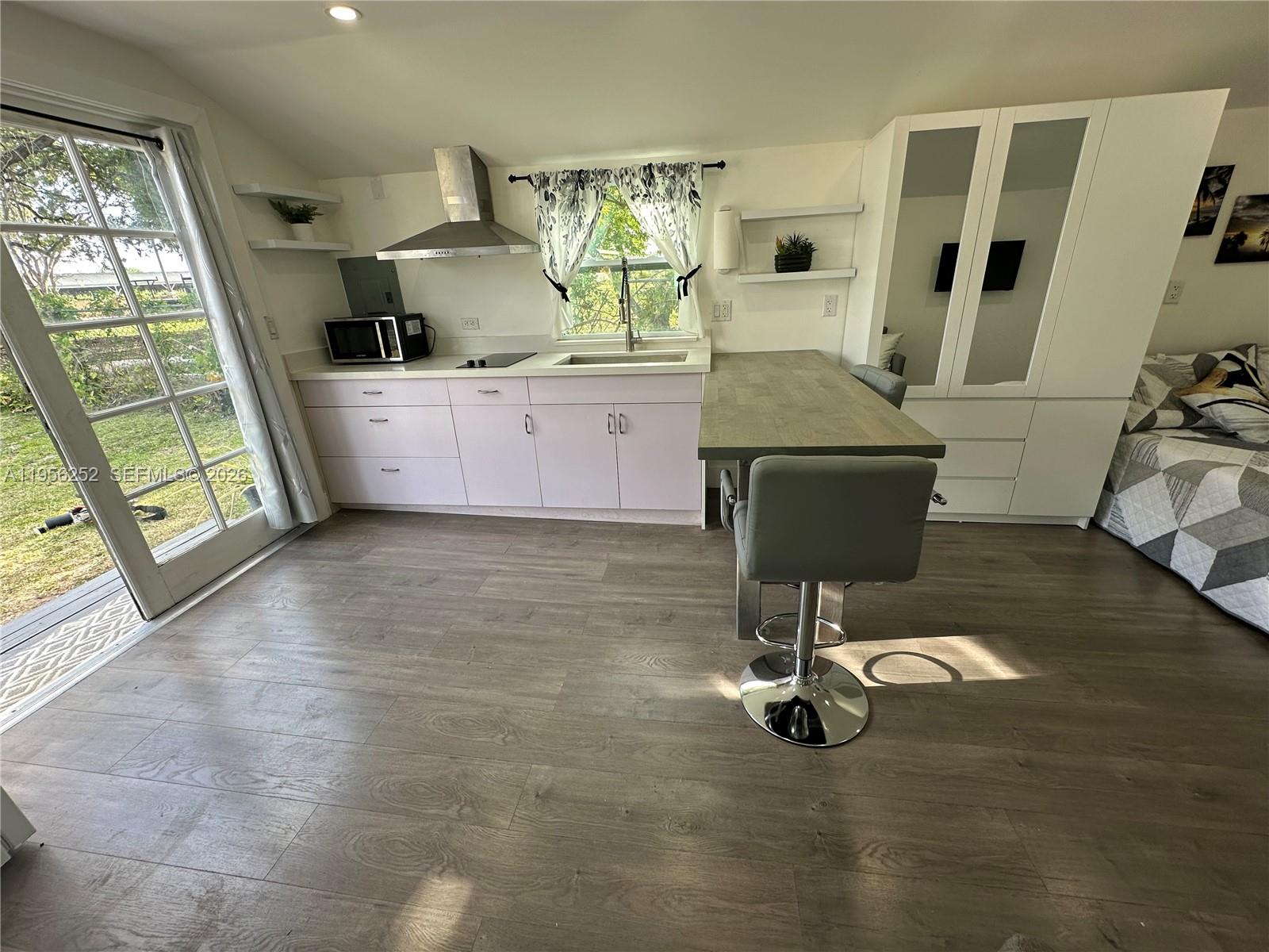 A studio apartment features a kitchenette with light cabinets, a breakfast bar, and a bed — 18481 SW 208th St # 0, Miami FL 33187, MIAMI, FL