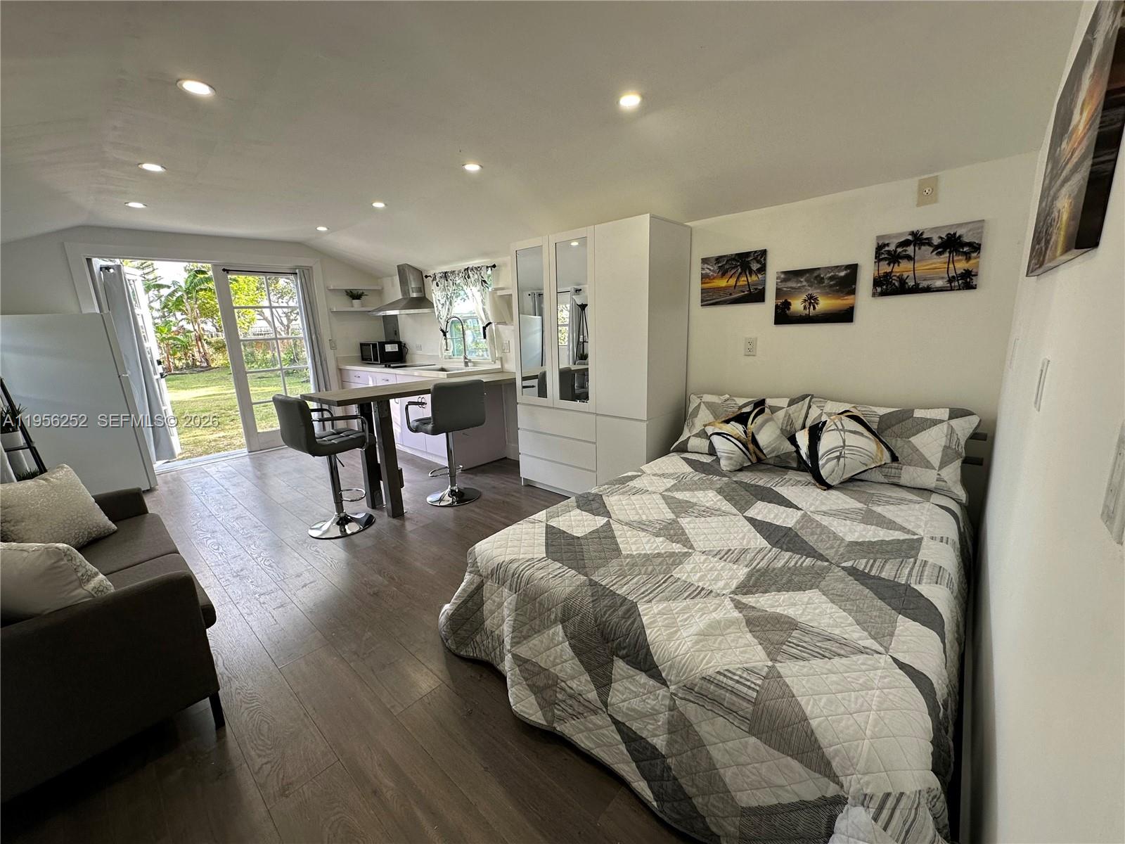 A studio apartment features a bed, a small kitchen with bar seating, and glass doors — 18481 SW 208th St # 0, Miami FL 33187, MIAMI, FL