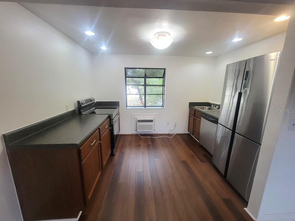A kitchen features dark wood cabinets, dark countertops, stainless steel appliances, and wood-look flooring — 2142 BRADFORD STREET UNIT 325, CLEARWATER, FL