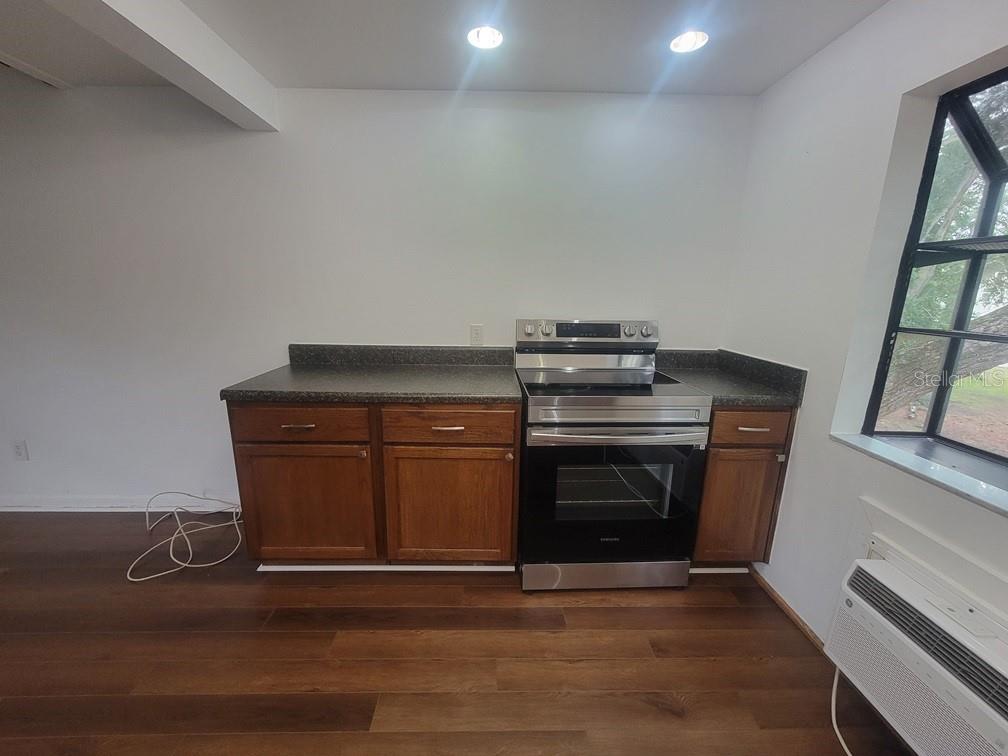 A kitchen features wood cabinets, a stainless steel range, and dark countertops on wood flooring — 2142 BRADFORD STREET UNIT 325, CLEARWATER, FL