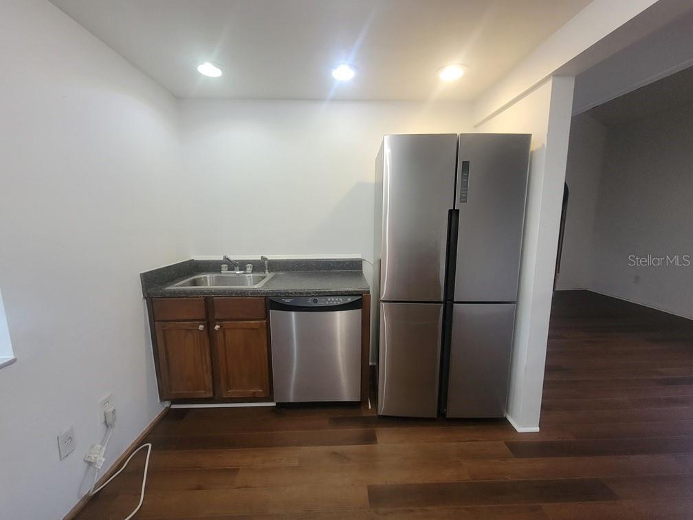 A small kitchen area features a stainless steel refrigerator, dishwasher, sink, and wood cabinets — 2142 BRADFORD STREET UNIT 325, CLEARWATER, FL