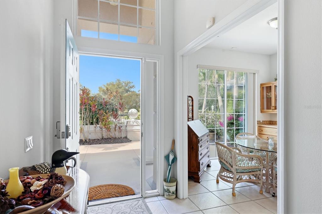 An entryway opens to a dining area with tile floors and a view of landscaping — 7119 KENSINGTON COURT, UNIVERSITY PARK, FL