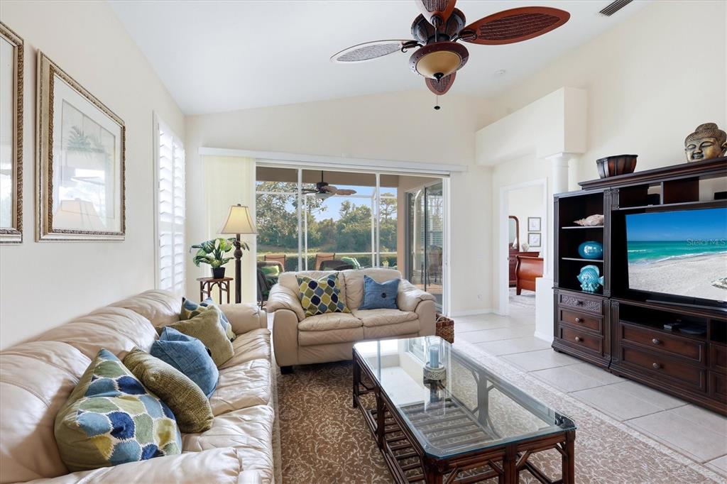 A living room features a beige sofa, glass coffee table, and a large entertainment center — 7119 KENSINGTON COURT, UNIVERSITY PARK, FL