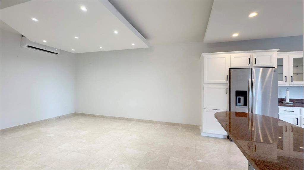 An open-plan kitchen and living area features light tile flooring and recessed ceiling lighting — 1-02 CAOBA STREET UNIT 312-6, GUAYNABO, PR