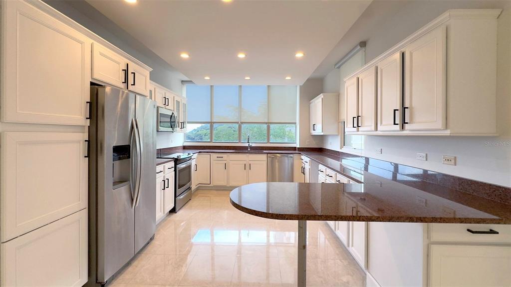 A kitchen features white cabinets, granite countertops, stainless steel appliances, and a large window — 1-02 CAOBA STREET UNIT 312-6, GUAYNABO, PR