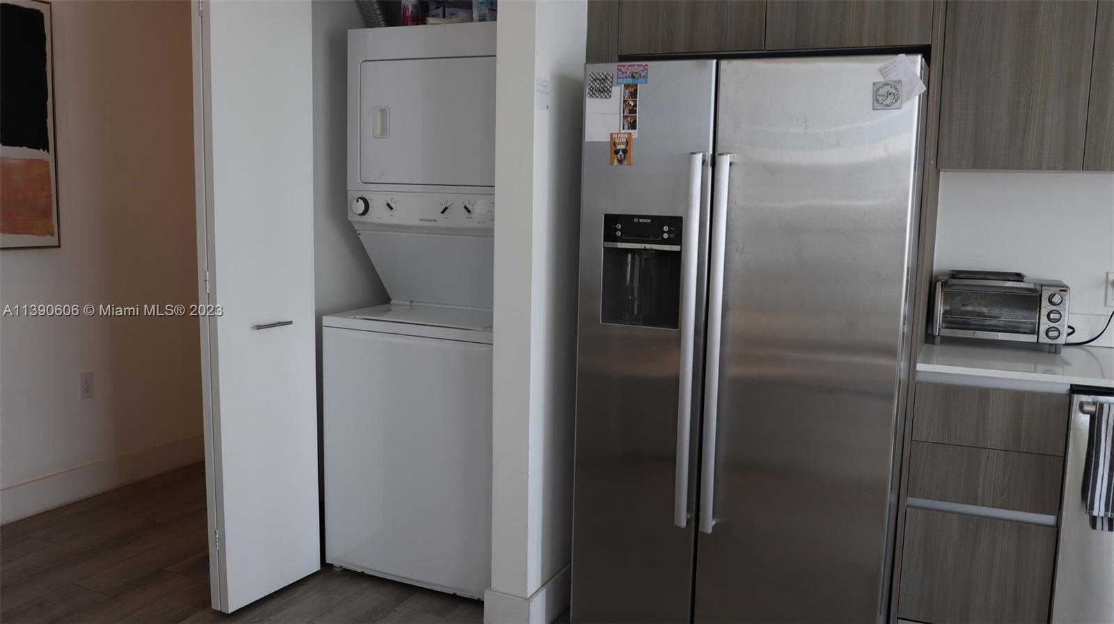 A kitchen area features a stacked laundry unit next to a stainless steel refrigerator — 201 SW 17th Rd # 606, Miami FL 33129, MIAMI, FL