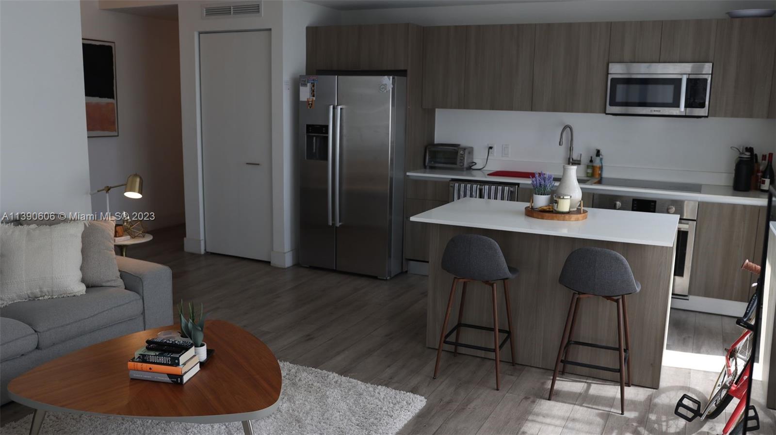 This open-concept kitchen and living area features wood-tone cabinetry, stainless steel appliances, and a breakfast bar — 201 SW 17th Rd # 606, Miami FL 33129, MIAMI, FL