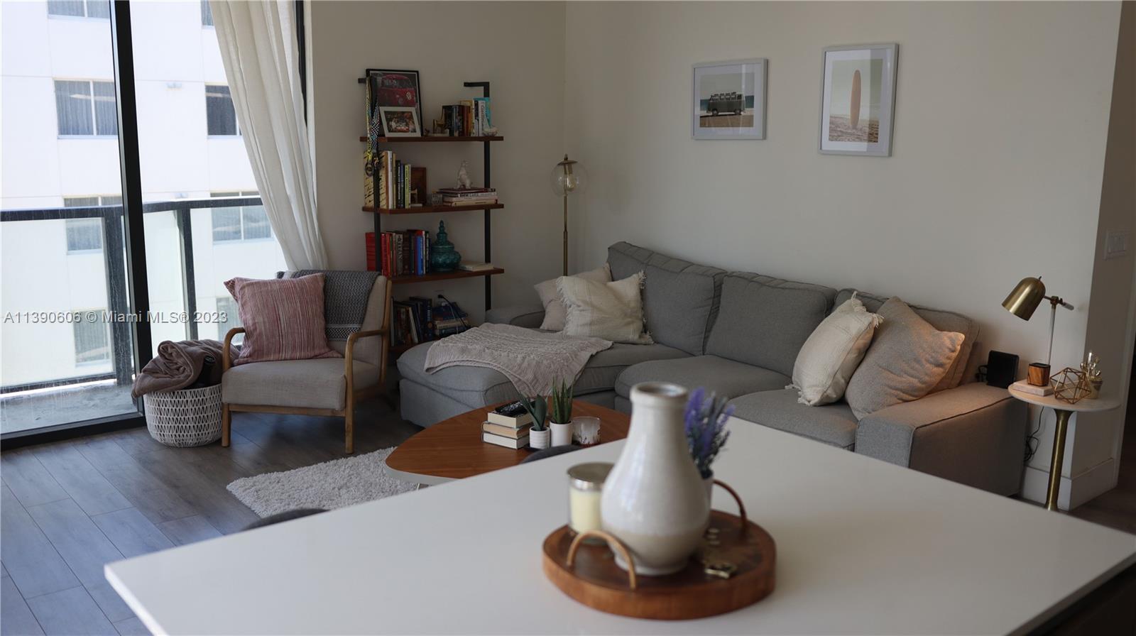 A living room features a gray sectional sofa, an armchair, a bookshelf, and a balcony — 201 SW 17th Rd # 606, Miami FL 33129, MIAMI, FL