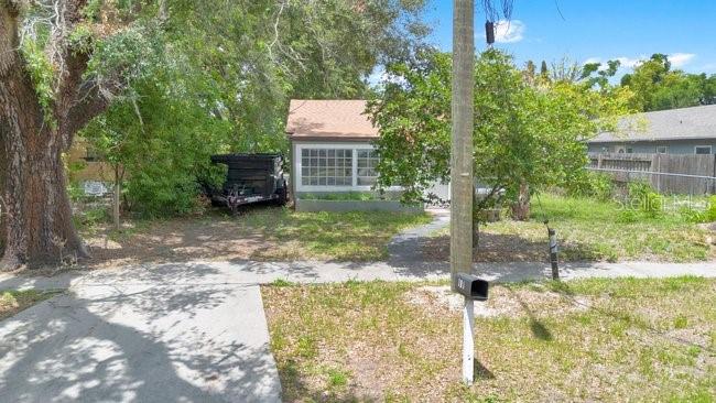 A small house with a light-colored exterior sits behind a tree-lined yard and sidewalk — 619 GRAND STREET, ORLANDO, FL