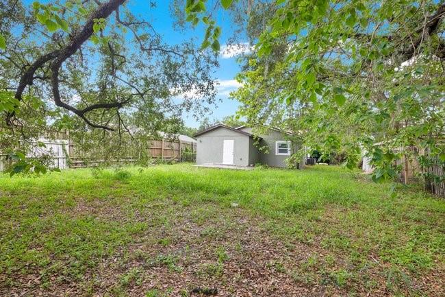 A gray house with a white door sits in a large, grassy backyard with trees — 619 GRAND STREET, ORLANDO, FL