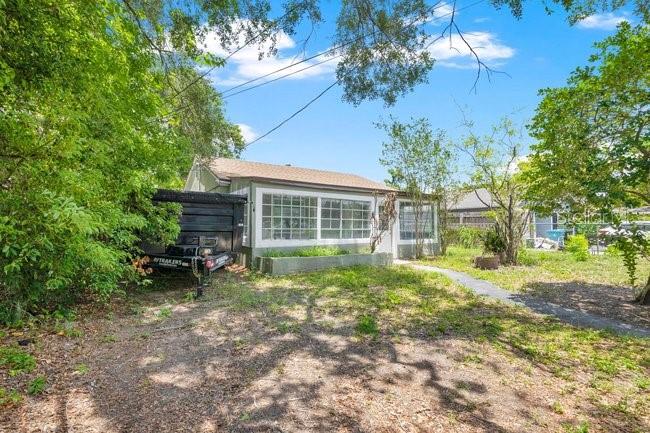 A small, single-story house with a screened-in porch sits on a grassy lot with trees — 619 GRAND STREET, ORLANDO, FL