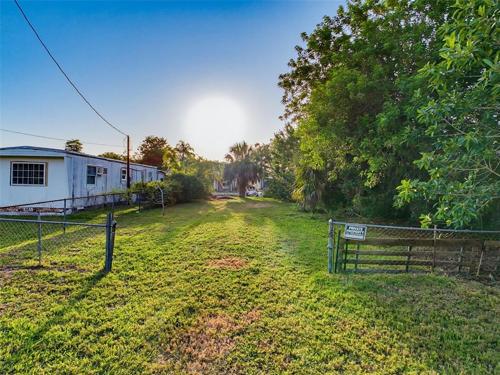 A grassy lot features a chain-link fence, a private property sign, and a mobile home — 14905 OLD DIXIE HIGHWAY, HUDSON, FL