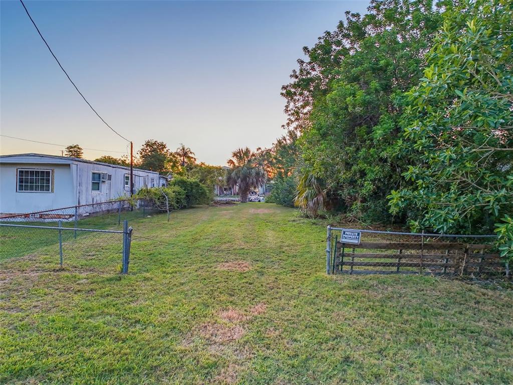 A grassy, fenced-in lot sits next to a white mobile home under a clear sky — 14905 OLD DIXIE HIGHWAY, HUDSON, FL