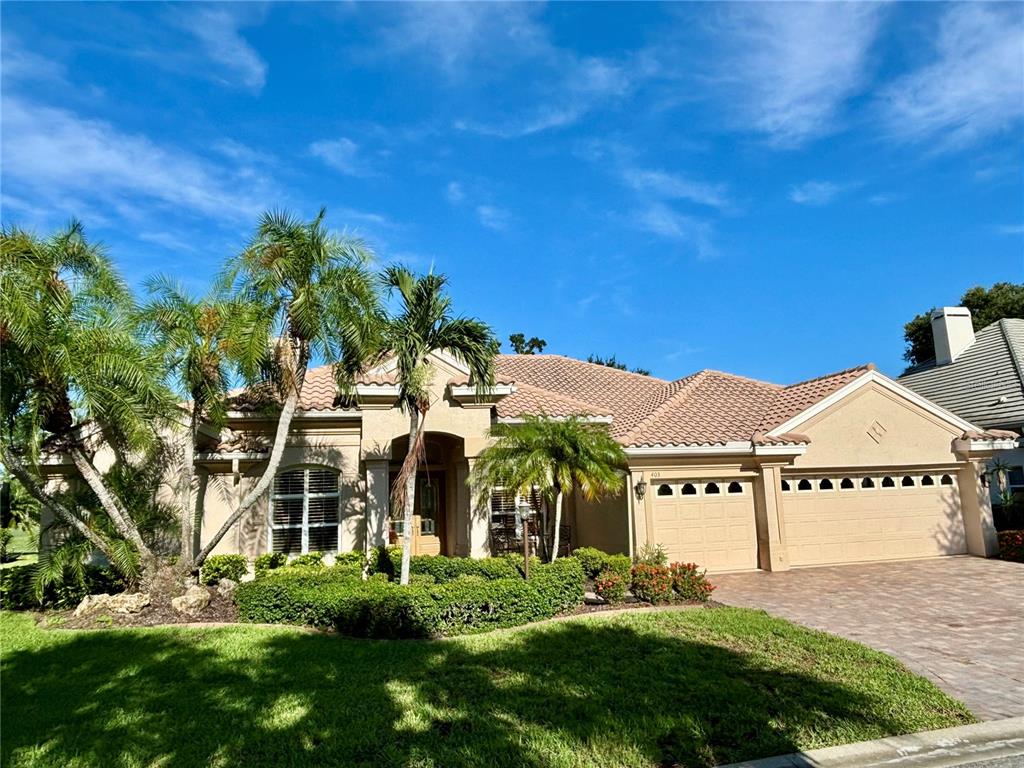 A single-story beige house with a tiled roof, three-car garage, and a paved driveway — 403 LANSBROOK DRIVE, VENICE, FL