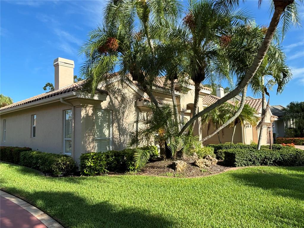 A covered entryway features a paved patio, double front doors, and a small bistro seating area — 403 LANSBROOK DRIVE, VENICE, FL